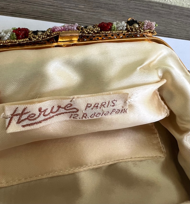 May include: A vintage beaded evening bag with a gold metal frame and a satin lining. The bag has a label that reads "Herm&eacute;s Paris 12, Rue de la Paix".