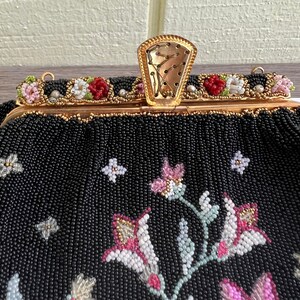 May include: A black beaded evening bag with a floral design. The bag has a gold clasp and a chain strap.