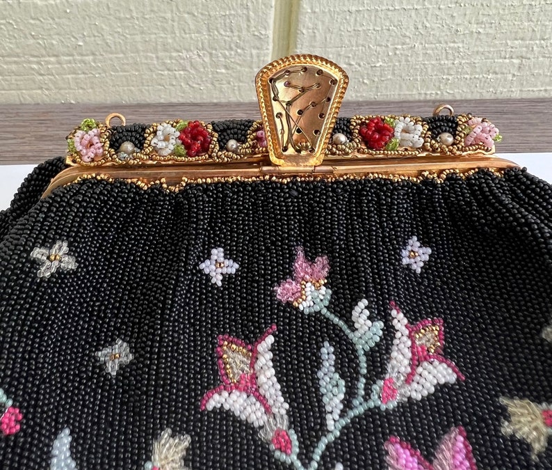 May include: A black beaded evening bag with a floral design. The bag has a gold clasp and a chain strap.