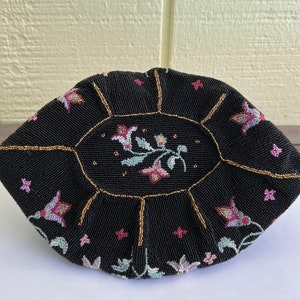 May include: A black beaded purse with a floral design. The purse is round and has a gold trim.