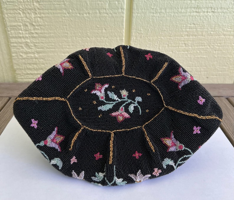 May include: A black beaded purse with a floral design. The purse is round and has a gold trim.