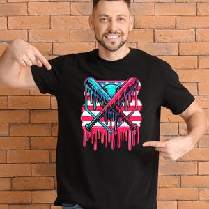 Peut inclure: T-shirt noir avec un motif de battes de baseball croisées bleues et rouges, avec un design de balle de baseball et de drapeau américain. Le motif a un effet dégoulinant. Le t-shirt est porté par une personne.