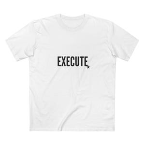 May include: White t-shirt with the word "EXECUTE" in bold, black capital letters. A small black star is to the right of the word. The shirt has a crew neck and short sleeves.