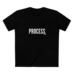 May include: Black t-shirt with the word "PROCESS" in white, accompanied by a small white star. The shirt has short sleeves and a crew neck. The fabric appears to be a soft, comfortable material.