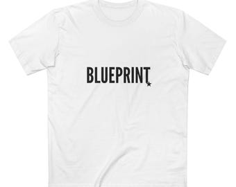 May include: White t-shirt with the word "BLUEPRINT" in bold black letters and a small black star to the right. The shirt has a crew neck and short sleeves.