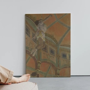 Può includere: Una donna si rilassa in una poltrona a sacco beige, guardando un dipinto incorniciato di una persona appesa a un soffitto. Il dipinto è in una tavolozza di colori tenui con sfumature di arancione, verde e marrone.