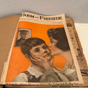 May include: A vintage January 1919 Farm and Fireside magazine with an orange cover featuring an illustration of a person kissing a child on the cheek, a small inset portrait of a person in a military uniform, and the text What the Ships Mean to You.