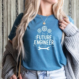 Könnte beinhalten: Ein blaues T-Shirt mit einem weißen Grafikdesign, auf dem "FUTURE ENGINEER" mit einem Schraubenschlüssel und Zahnrädern steht.
