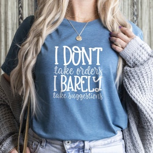 May include: A blue t-shirt with white text that reads "I don't take orders I barely take suggestions".