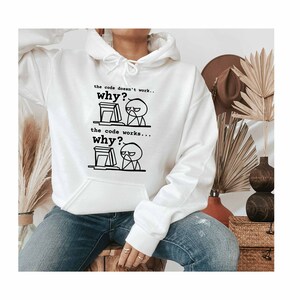 Pu&ograve; includere: Felpa con cappuccio bianca con una grafica nera di un omino davanti a un computer. Il testo recita "the code doesn't work... why?" e "the code works... why?"