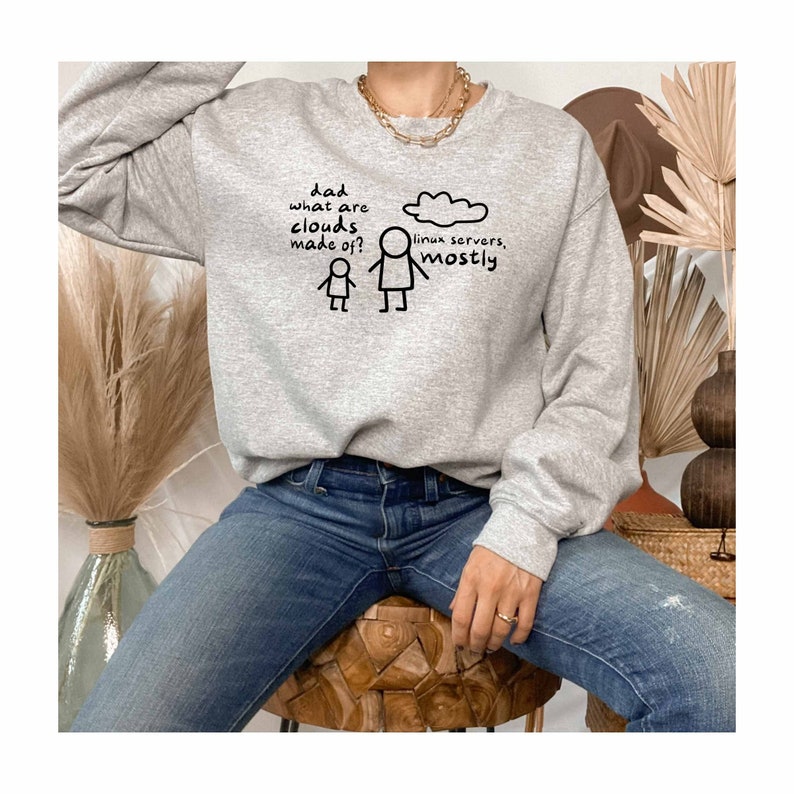 K&ouml;nnte beinhalten: Grauer Pullover mit einer humorvollen Illustration einer Strichm&auml;nnchenfigur, die fragt: "Papa, woraus bestehen Wolken?" und einer anderen Strichm&auml;nnchenfigur, die antwortet: "Meistens aus Linux-Servern."