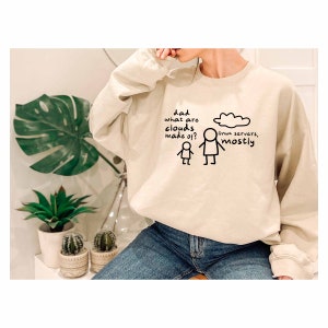 K&ouml;nnte beinhalten: Ein beiger Pullover mit einer humorvollen Grafik zum Thema Cloud Computing. Die Grafik zeigt eine Strichm&auml;nnchen, die fragt "Papa, woraus bestehen Wolken?" und ein anderes Strichm&auml;nnchen, das auf eine Wolke zeigt mit dem Text "Linux-Server, haupts&auml;chlich".