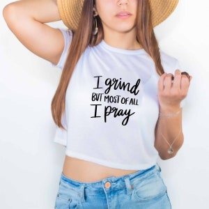 May include: White cropped t-shirt with black text that reads "I grind but most of all I pray".