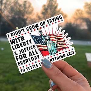 Peut inclure: Un autocollant blanc avec le texte "I didn't grow up saying with liberty & justice for all everyday to settle for anything less." L'autocollant repr&eacute;sente la Statue de la Libert&eacute; et un drapeau am&eacute;ricain.