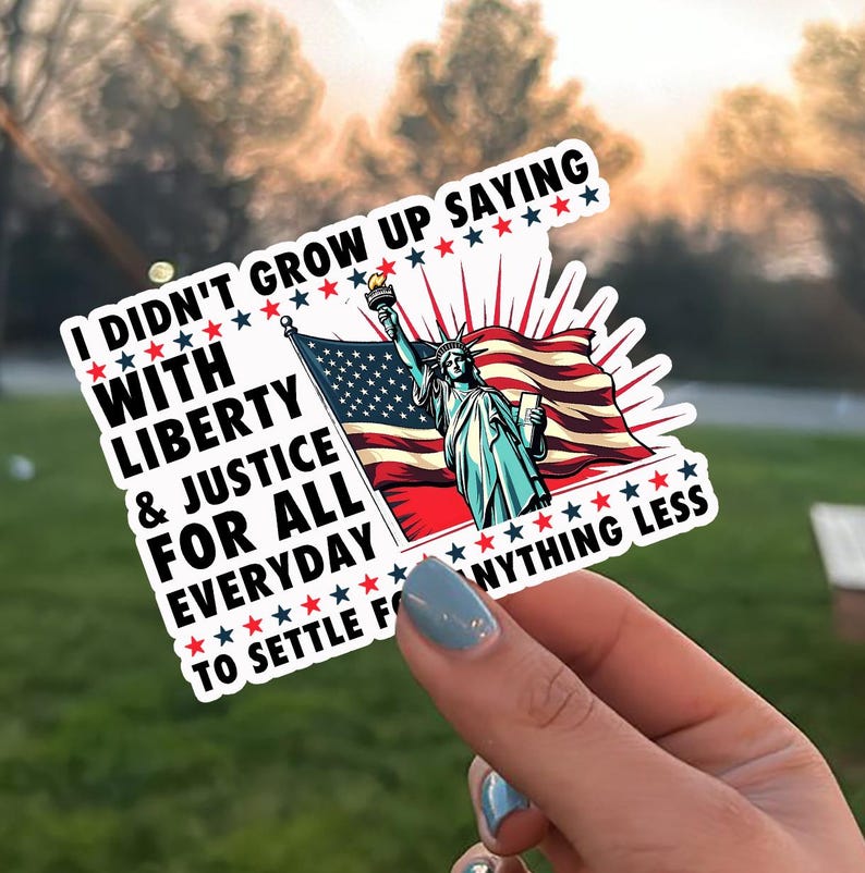 Peut inclure: Un autocollant blanc avec le texte "I didn't grow up saying with liberty & justice for all everyday to settle for anything less." L'autocollant repr&eacute;sente la Statue de la Libert&eacute; et un drapeau am&eacute;ricain.