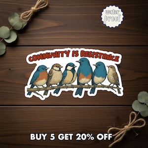 May include: A sticker featuring six colorful birds perched on a branch. The text "COMMUNITY IS RESISTANCE" is above the birds. A small "water proof" label is in the upper right corner. The bottom of the sticker reads "BUY 5 GET 20% OFF".