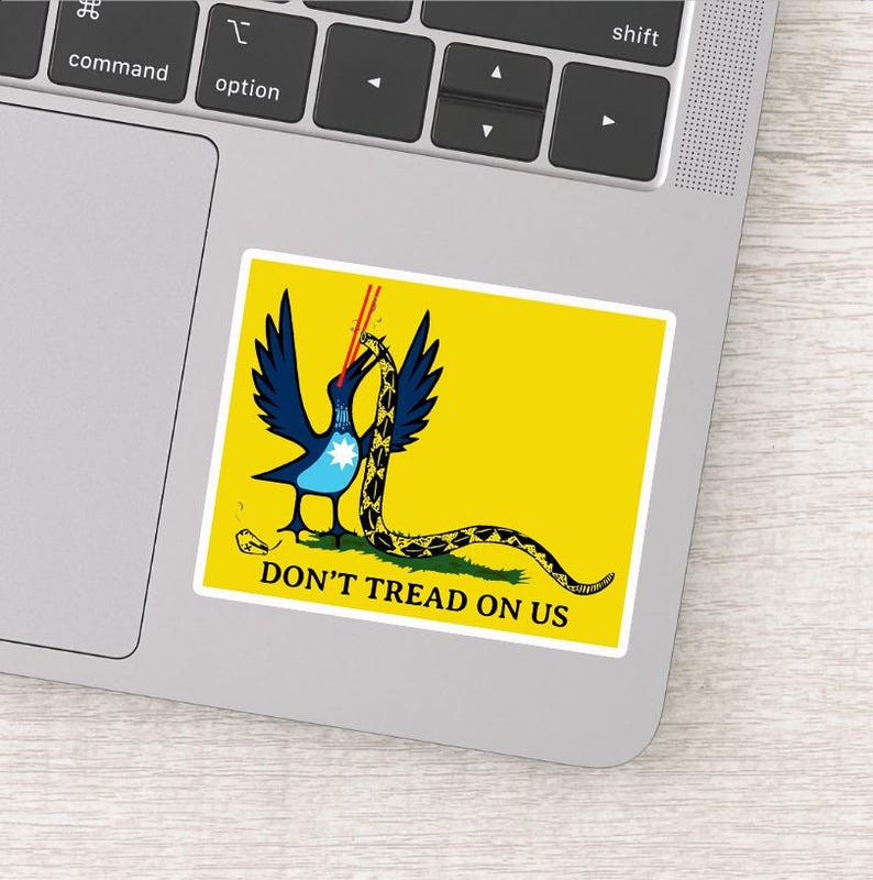 May include: A yellow sticker featuring a blue bird with outstretched wings, a snake, and the text "DON'T TREAD ON US." The bird has a white star on its chest and is holding the snake. The snake is yellow and black.