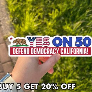 May include: A sticker with the text "YES ON 50" in blue and red, with the words "DEFEND DEMOCRACY CALIFORNIA!" below. The sticker features a brown bear and a red star.
