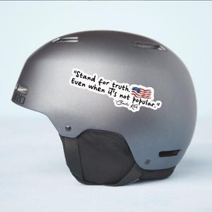 May include: A gray Giro ski helmet with a sticker that reads "Stand for truth. Even when it's not popular." and an American flag graphic. The quote is attributed to Charlie Kirk.