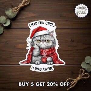 May include: A sticker featuring a grumpy gray cat wearing a Santa hat and a red scarf with white snowflakes. The cat is holding a cup of hot beverage. Text on the sticker reads "I HAD FUN ONCE... IT WAS AWFUL". The sticker is waterproof.