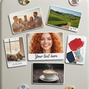 May include: A collection of rectangular magnets with various images. One features a group of people on a beach, another a landscape, and a third a woman with red hair. Other magnets include a cat, abstract art, and a coffee cup.