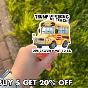 May include: A yellow school bus sticker with the text "TRUMP IS EVERYTHING WE TEACH" above the bus and "OUR CHILDREN NOT TO BE" below. The bus has a stop sign and the words "SCHOOL BUS" on top.