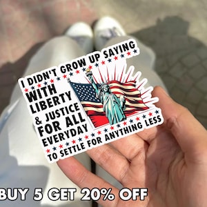 Peut inclure: Un autocollant avec la Statue de la Libert&eacute; et le drapeau am&eacute;ricain. Le texte sur l'autocollant dit : "I didn't grow up saying with liberty & justice for all everyday to settle for anything less."