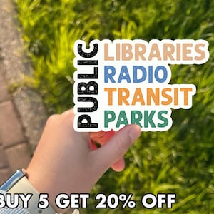 May include: A white sticker with the words "PUBLIC" in black and "LIBRARIES RADIO TRANSIT PARKS" in various colors. The sticker is held in front of a green grassy background. The text "BUY 5 GET 20% OFF" is at the bottom.