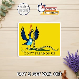May include: A yellow sticker featuring a stylized blue bird with a snake in its beak, set against a yellow background. The text "DON'T TREAD ON US" is below the bird. Additional text reads "BUY 5 GET 20% OFF".
