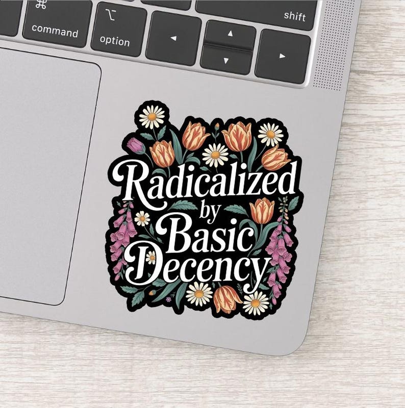 May include: A sticker with the text "Radicalized by Basic Decency" in a black and white design. The text is surrounded by a floral border of orange tulips, white daisies, and purple flowers.