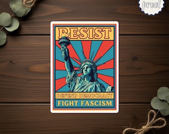 May include: A rectangular sticker featuring the Statue of Liberty with the word "RESIST" above and "DEFEND DEMOCRACY FIGHT FASCISM" below. The background has a red and blue burst design. The sticker is labeled "water proof".