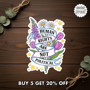 May include: A waterproof sticker with a floral design and the text "HUMAN RIGHTS ARE NOT POLITICAL." The sticker features a bouquet of flowers, including daisies, tulips, and foxgloves, with a banner displaying the message. Yellow stars surround the floral arrangement.