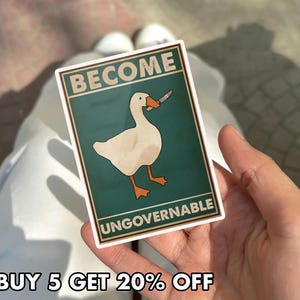 May include: A rectangular sticker featuring a white goose with an orange beak and feet, holding a knife in its beak. The sticker has the words "BECOME UNGOVERNABLE" and "BUY 5 GET 20% OFF" in a bold font.