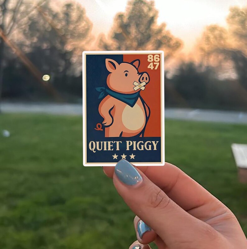 May include: A rectangular sticker featuring a cartoon pig with a bandage over its mouth and a blue bandana. The sticker has a navy blue and red background with the words "QUIET PIGGY" and three stars at the bottom. The numbers "86" and "47" are in the top right corner.