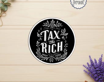 May include: A round, black sticker with white text that reads "TAX THE RICH" in a decorative font. The sticker is surrounded by a white border and floral accents. A smaller, water-proof sticker is in the upper right corner.