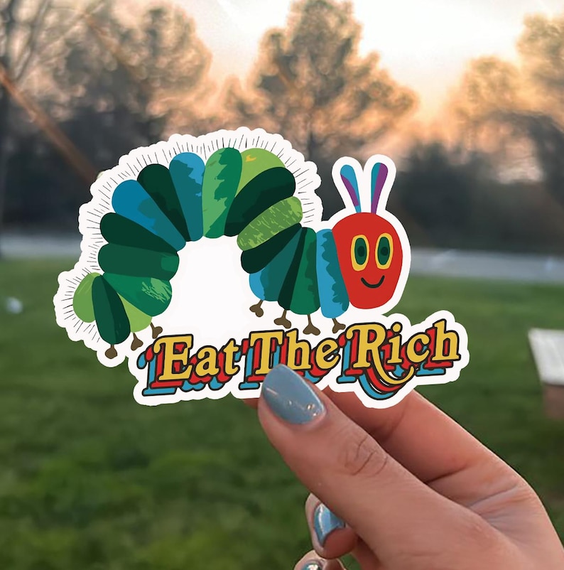 May include: A colorful sticker featuring a cartoon caterpillar with a red face and blue and green body segments. The sticker has the text "Eat The Rich" in a playful, multi-colored font.