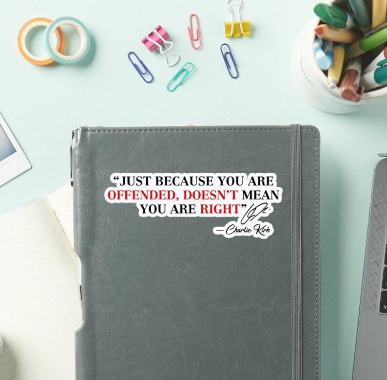May include: A gray notebook with the quote "JUST BECAUSE YOU ARE OFFENDED, DOESN'T MEAN YOU ARE RIGHT" by Charlie Kirk. The image also shows colorful office supplies like paper clips and tape.