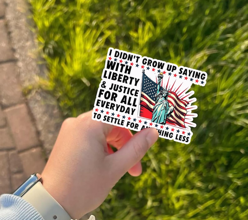 Peut inclure: Un autocollant repr&eacute;sentant la Statue de la Libert&eacute; et le drapeau am&eacute;ricain. L'autocollant porte le texte "I didn't grow up saying with liberty & justice for all everyday to settle for anything less."
