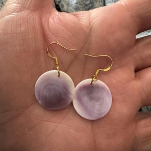 May include: A pair of purple and white shell earrings with gold hooks.