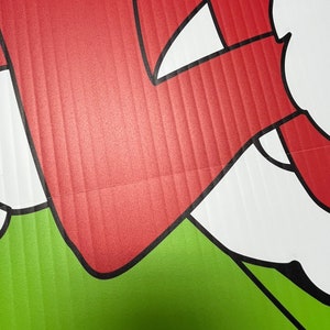 May include: A red and white cartoon character with a black outline. The character is on a green background.