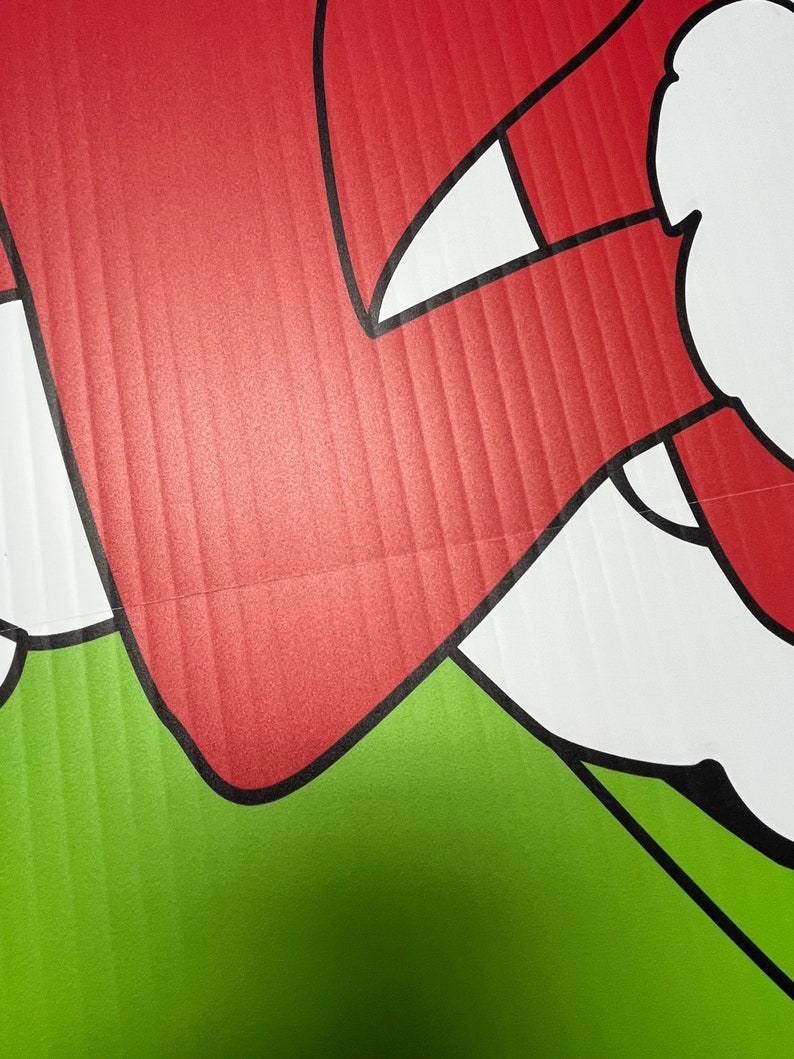 May include: A red and white cartoon character with a black outline. The character is on a green background.