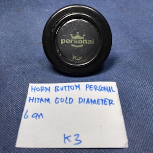 May include: A black horn button with the word "personal" in gold lettering, a crown graphic, and a horn symbol. The button has a diameter of 6 cm.