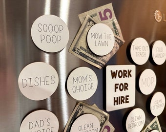 May include: A white refrigerator door with several round white magnets with black text. The magnets have phrases like "Scoop Poop", "Mow the Lawn", "Dishes", "Mom's Choice", "Take Out Trash", "Fold Laundry", "Clean Bedroom", "Clean Litter Box", and "Mop". There is also a white square magnet with black text that says "Work for Hire".