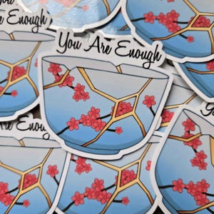 May include: A sticker featuring a stylized illustration of a broken bowl, repaired with gold lines, and adorned with red cherry blossoms. The text "You Are Enough" is written in elegant script across the top of the sticker.
