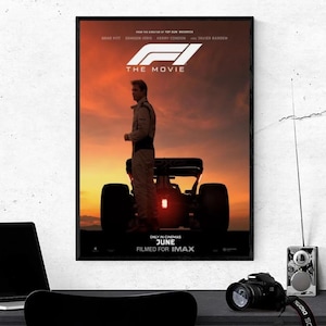 Könnte beinhalten: Gerahmtes Filmplakat für "F1: The Movie" mit einem Fahrer vor einem Rennwagen. Das Poster zeigt den Text "The Movie", "Juni" und "Filmed for IMAX" vor einem Sonnenuntergang.