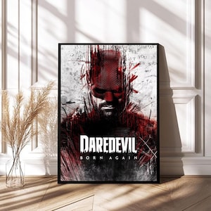 May include: A framed poster featuring a stylized image of Daredevil. The artwork is predominantly red and black, with a portrait of the character and the text "DAREDEVIL BORN AGAIN". The background has a textured, distressed appearance.