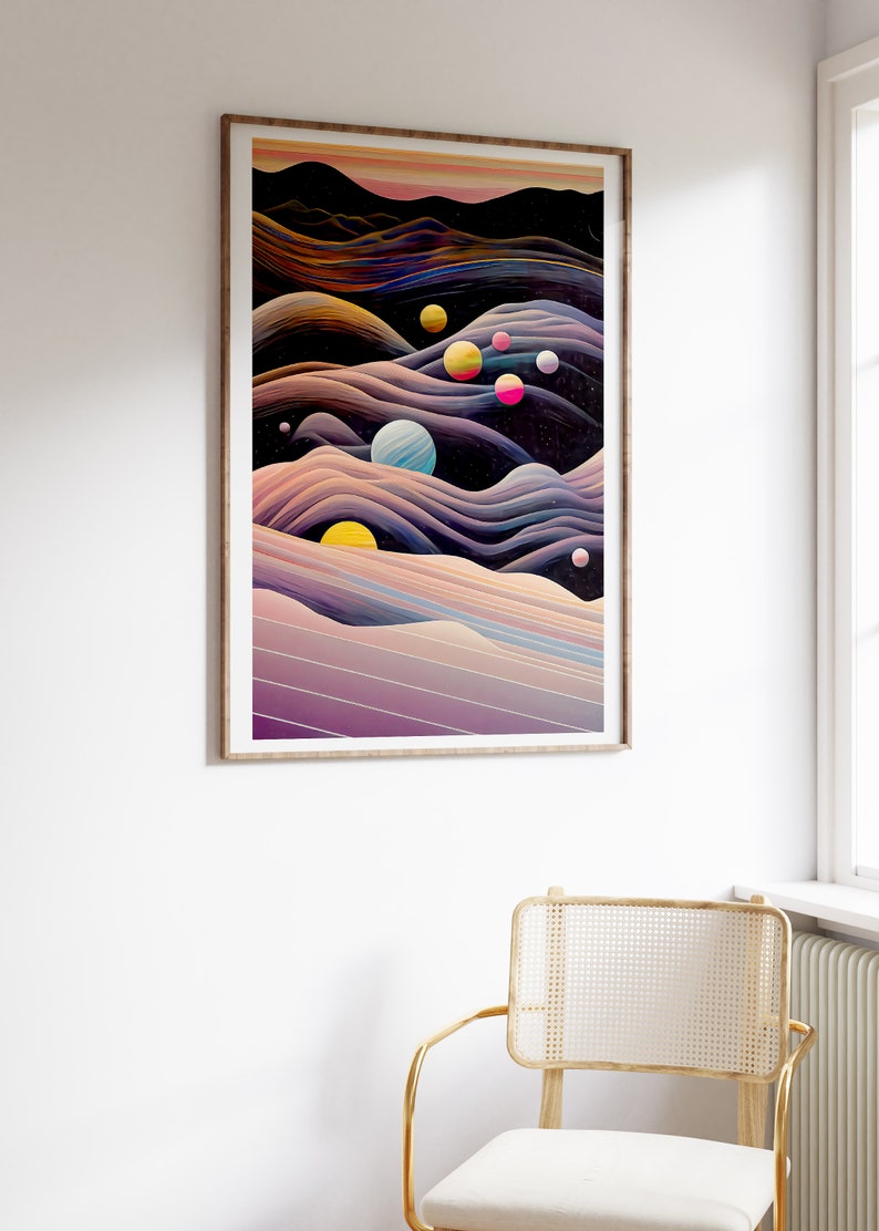May include: Abstract art print featuring a dark blue background with colourful planets and swirling lines in shades of purple, pink, yellow, and orange. The print is framed in a light wood frame.