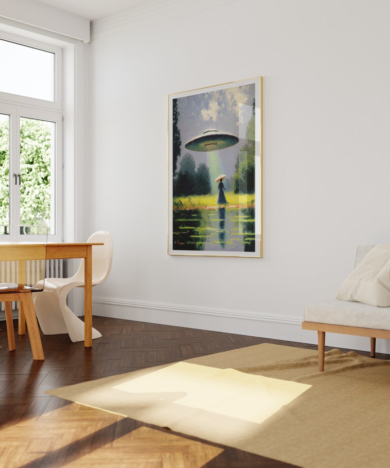Op de afbeelding: Een ingelijst schilderij van een vrouw in een blauwe jurk die naar een vliegende schotel in een groen veld loopt. De schotel zweeft boven de vrouw en schijnt een lichtstraal op haar. Het schilderij hangt aan een witte muur in een kamer met een houten vloer.