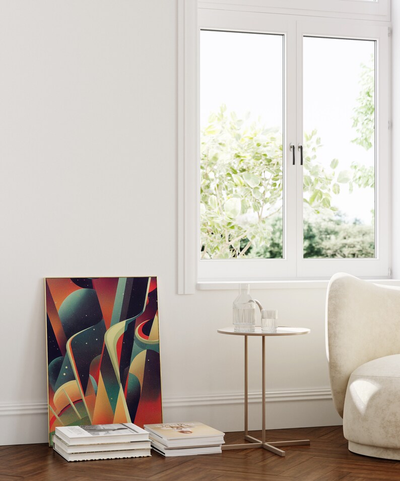 May include: A framed abstract art print with geometric shapes and colors in shades of red, orange, yellow, green, and blue. The print is hanging on a white wall next to a window. A small round side table with a glass top and a gold metal base is in front of the print. A stack of books is on the floor below the print.