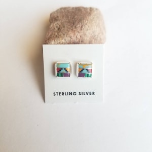 May include: Square sterling silver stud earrings with a mosaic design in turquoise, purple, green, and yellow. The earrings are displayed on a white card with the text "STERLING SILVER".